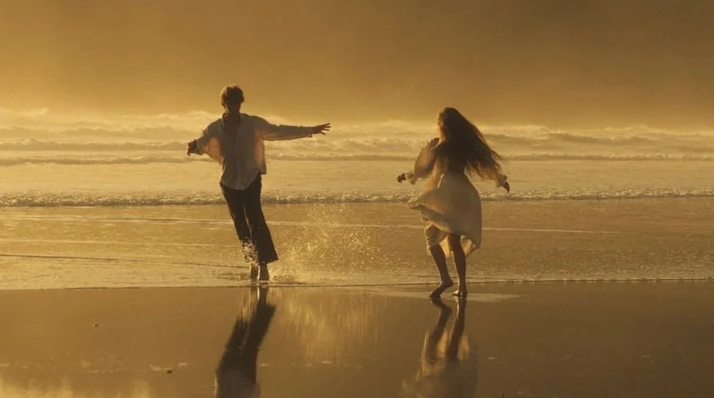 A couple joyfully runs on a sunlit beach, creating splashes in the water. The warm golden light and ocean waves evoke a sense of freedom and happiness.
